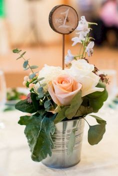 a flower arrangement in a bucket on top of a table