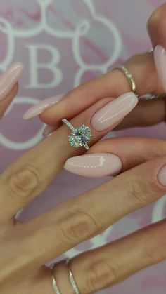 a woman's hands with pink manies and rings on their fingers, holding an engagement ring