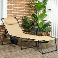 a tan chaise lounge chair sitting on top of a hard wood floor next to a brick wall