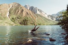 a person swimming in a lake with mountains in the background