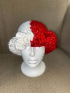 a crocheted red and white hat sitting on top of a mannequin head