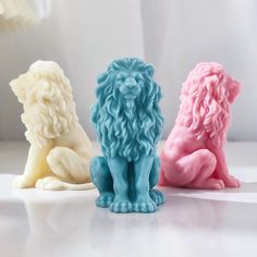 three different colored lion figurines sitting next to each other on a white surface