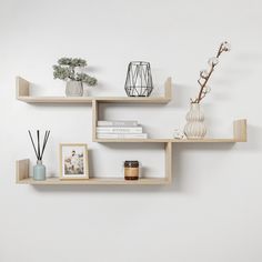 three wooden shelves with vases, candles and pictures on them against a white wall