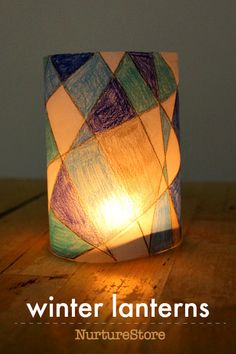 a lit candle that is sitting on top of a wooden table with the words winter lanterns written below it