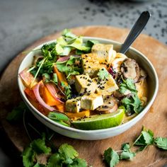 a white bowl filled with food on top of a wooden cutting board