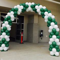 an arch made out of green and white balloons