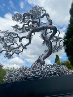 a metal tree sculpture sitting on top of a black table next to a blue sky