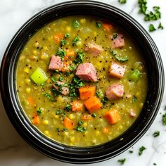 a bowl of soup with meat and vegetables in it on a white table top next to some parsley