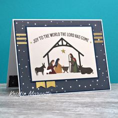 a christmas card with the nativity scene in blue and white, on top of a wooden table