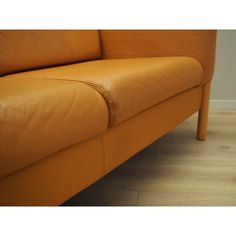 an orange leather couch sitting on top of a hard wood floor