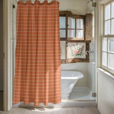 an orange and white shower curtain hanging in a bathroom next to a bathtub with a window