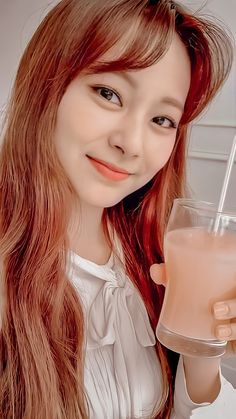 a young woman holding a glass of liquid