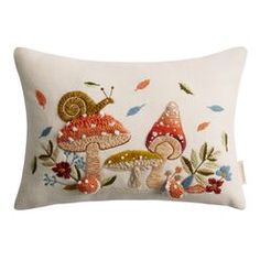 an embroidered pillow with mushrooms and leaves on it