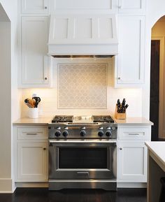 a stove top oven sitting inside of a kitchen next to white cabinets and counter tops