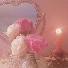 pink and white flowers in a glass vase on a table next to a mirror with a heart shaped frame