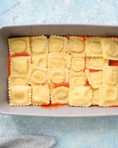 a pan filled with ravioli on top of a blue countertop next to a napkin