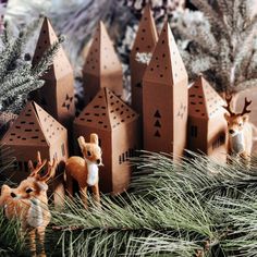 some little deer figurines are sitting in front of christmas trees and houses on display