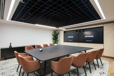 an empty conference room with chairs and a large table in front of a projector screen