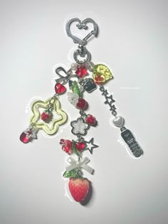 a key chain with various charms attached to it's sides and an apple hanging from the end