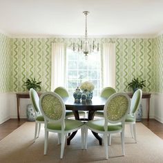 a dinning room table with green chairs in front of a wallpapered window