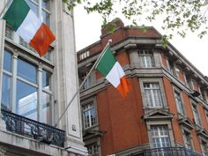 two flags are flying in front of some buildings