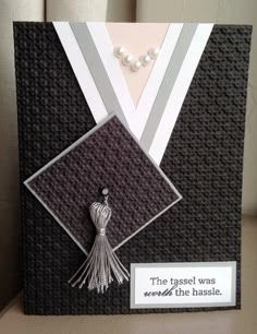 a graduation card with a tassel on the front and an ornament hanging from it