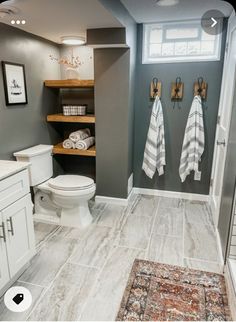 a bathroom with two towels hanging on the wall and a rug in front of it