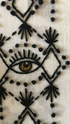 an eye is embroidered on the side of a piece of white fabric with black dots