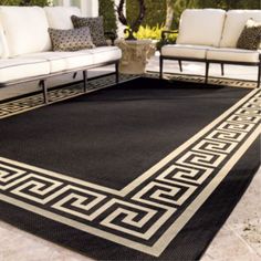 a black and white area rug with greek border on the ground next to couches