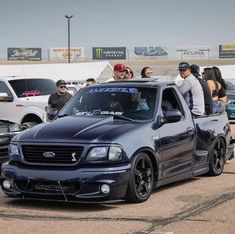 some people are standing in the back of a pick up truck at a car show