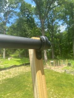 a close up of a telescope on a wooden pole in front of some grass and trees