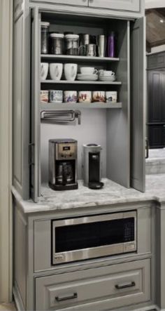 a kitchen with gray cabinets and white marble counter tops, coffee maker on the bottom shelf