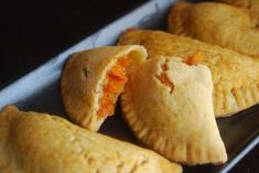 several pastries sitting on top of a baking pan covered in cheese and carrots