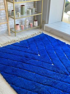 a bright blue rug is on the floor in front of a bookshelf and shelves