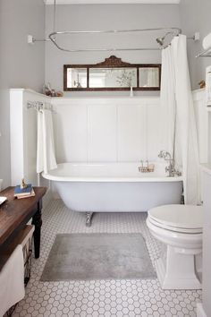 a white bath tub sitting under a chandelier next to a toilet and sink