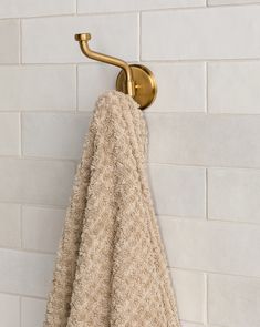 a gold towel hanging on a white brick wall