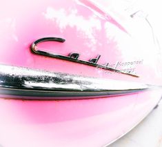 the hood ornament of a pink car with a black and white logo on it