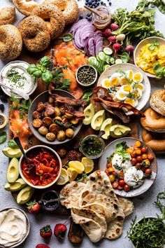 an assortment of food is laid out on a table with breads and other foods