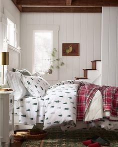 a bed sitting in a bedroom next to a window with lots of pillows on top of it