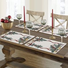 a wooden table topped with place mats covered in christmas decorations