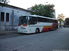 a bus is parked on the side of the road in front of an old building