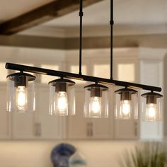 a kitchen light with five lights hanging from it's center beam and three glass jars on the bottom