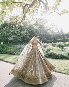 a woman in a bridal gown standing under a tree with her hands on her hips