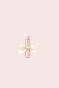 a pink lipstick with a white bow on it's side against a light pink background