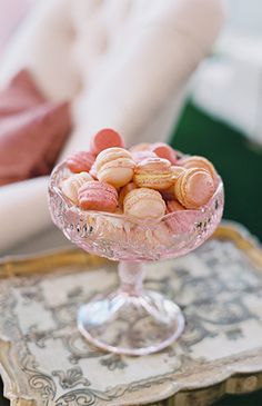 a glass bowl filled with candy sitting on top of a table next to a white chair