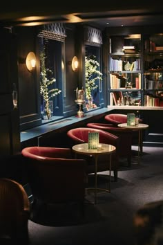 some chairs and tables in a room with books on the shelves behind them is a bookcase full of books