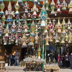 people are standing in front of a store with many colorful lights hanging from the ceiling