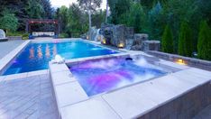 an outdoor swimming pool with waterfall and fire pit in the middle, surrounded by greenery