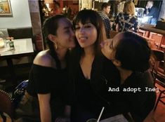 three women sitting next to each other at a table with drinks in front of them