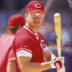 a man holding a baseball bat in his right hand and wearing a red jersey with the number 22 on it